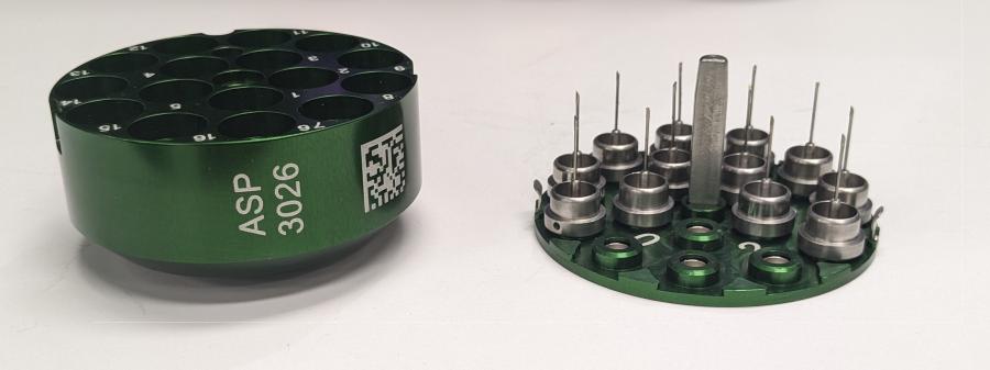 A green unipuck base and lid, with sample pins filling most of the magnetic positions on the unipuck lid